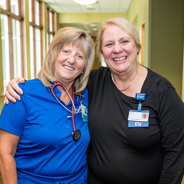Hospice and palliative health care professionals standing together, smiling in a hallway.