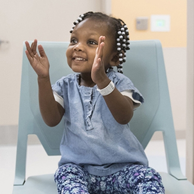 Smiling young Black girl claps her hands