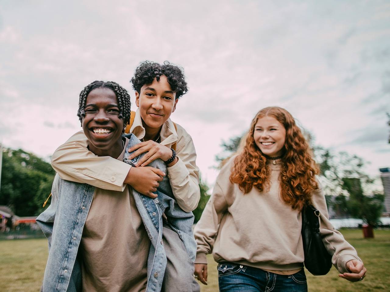 Two teenage boys and a teenage girl standing together outdoors