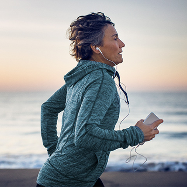 woman wearing light blue jacket running next to water