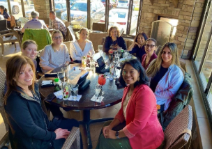 A group of women enjoying a meal together at a restaurant table, engaged in conversation and laughter.