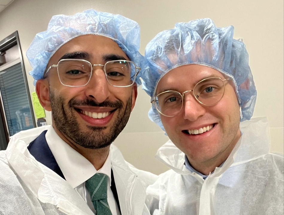 two residents with plastic head coverings smiling for a picture after a surgery