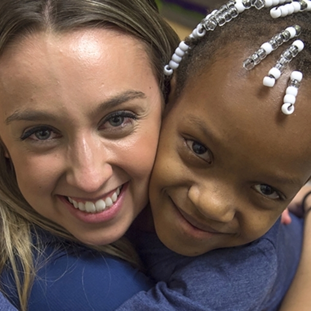 Smiling Black girl hugs smiling doctor in the pediatric fracture clinic