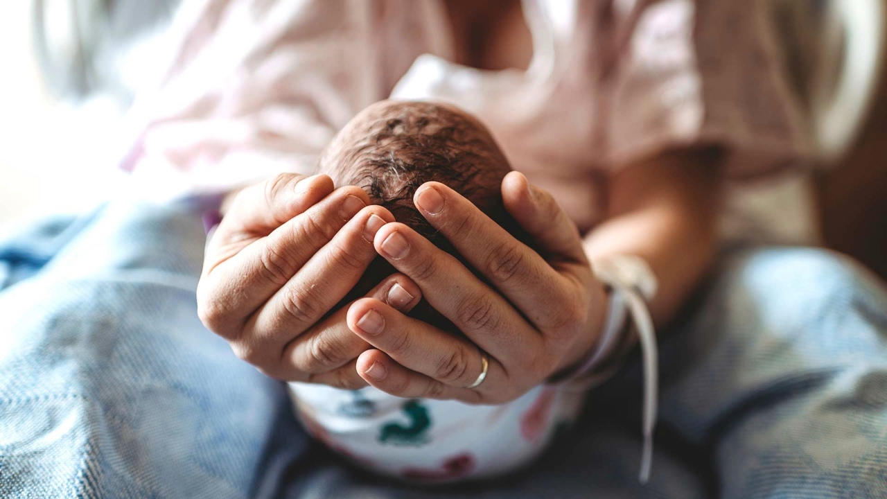 Close up photo of a mother's hands holding a newborn baby