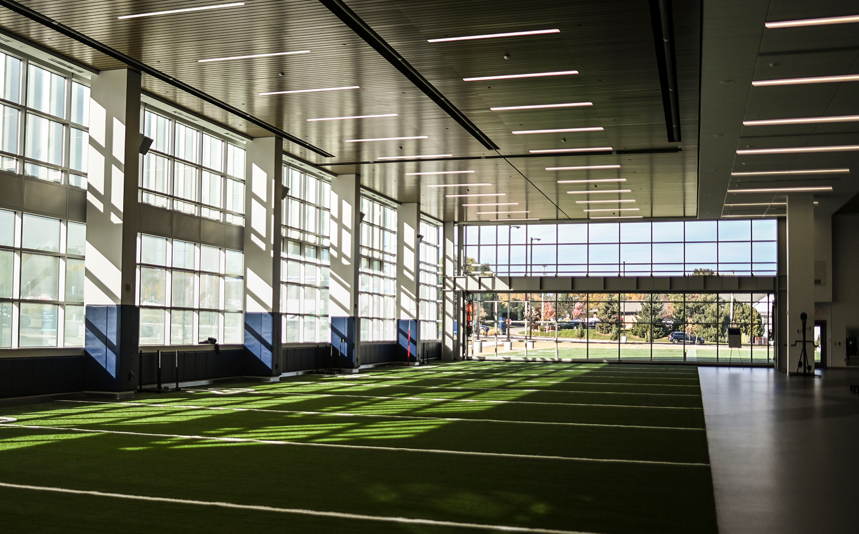 A spacious indoor football field featuring large windows, highlighting the facility's focus on sports medicine training.