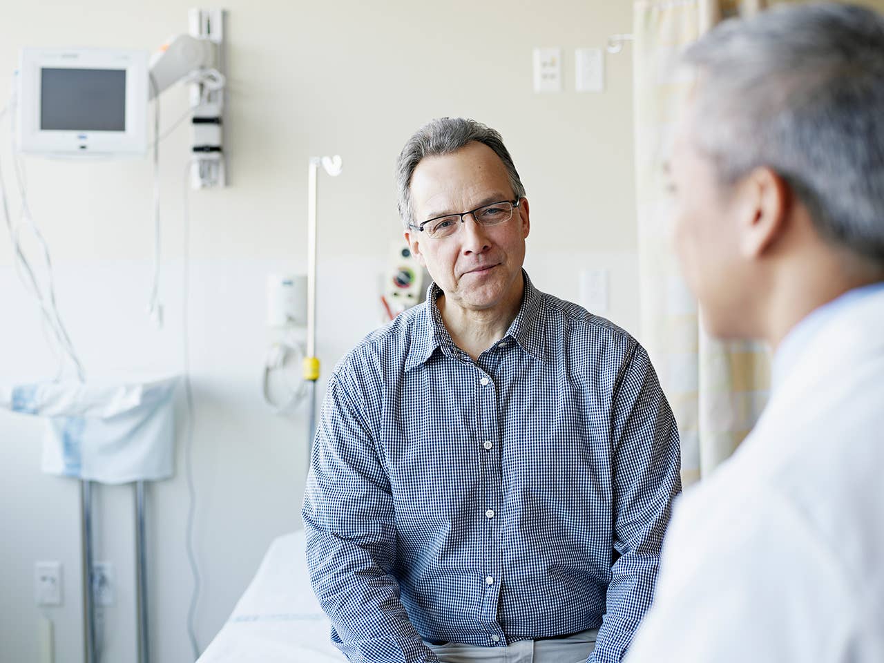 Man with glasses sits across from a doctor in a walk-in clinic exam room