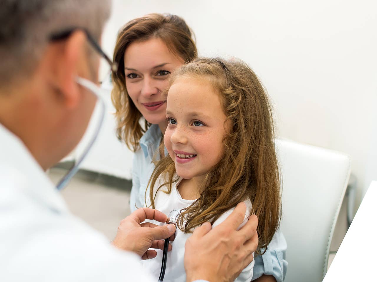 A doctor examines a young girl, who looks attentive and curious during the medical check-up.