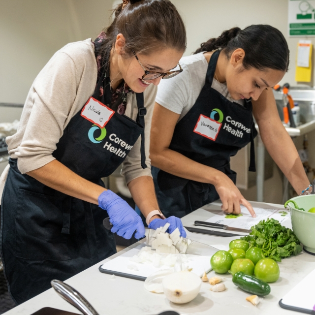 Two team members cutting vegetables while attending a cooking class