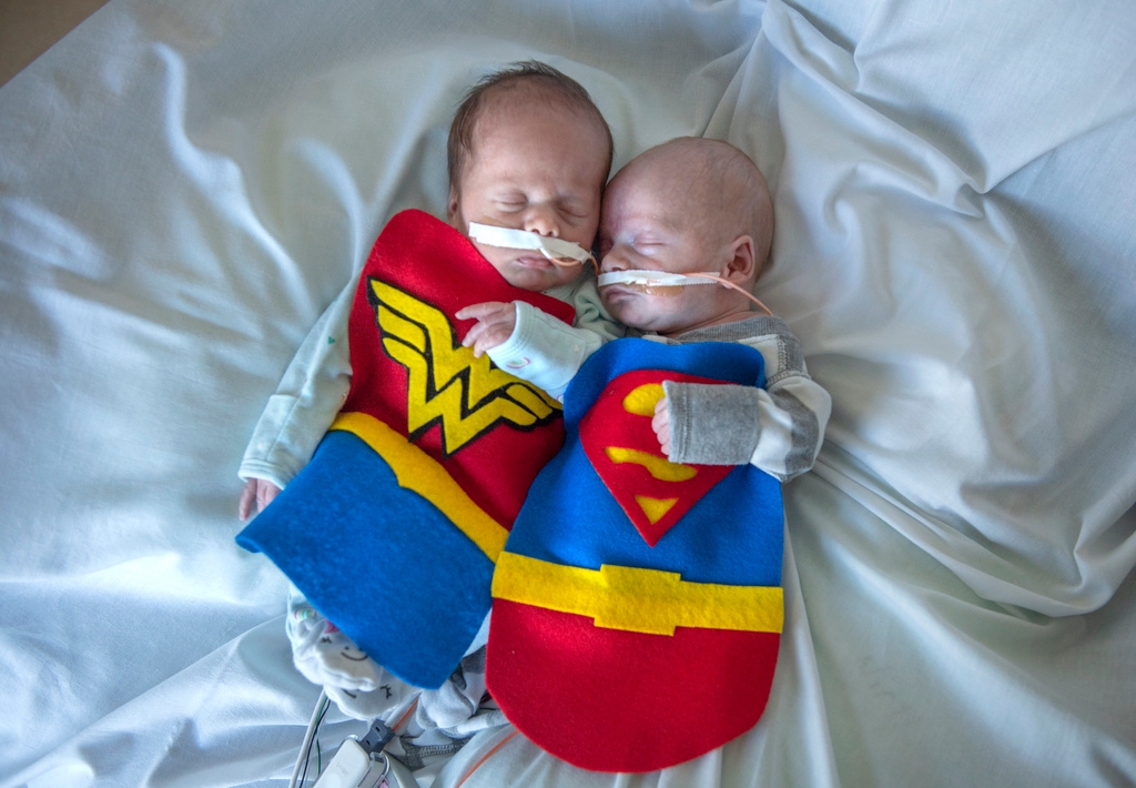 two babies in super hero costumes in the NICU