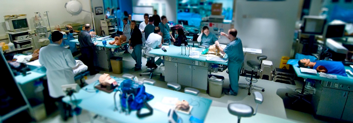 A group of medical residents engaged in a didactic conference within a hospital room, focusing on emergency medicine training.