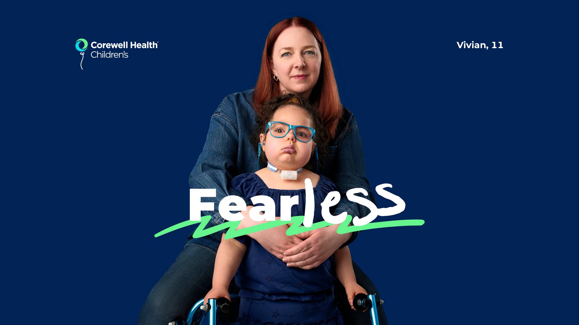 Vivian, an 11 year old patient wearing a blue blouse and light blue glasses, stands with a walker with her mom behind her