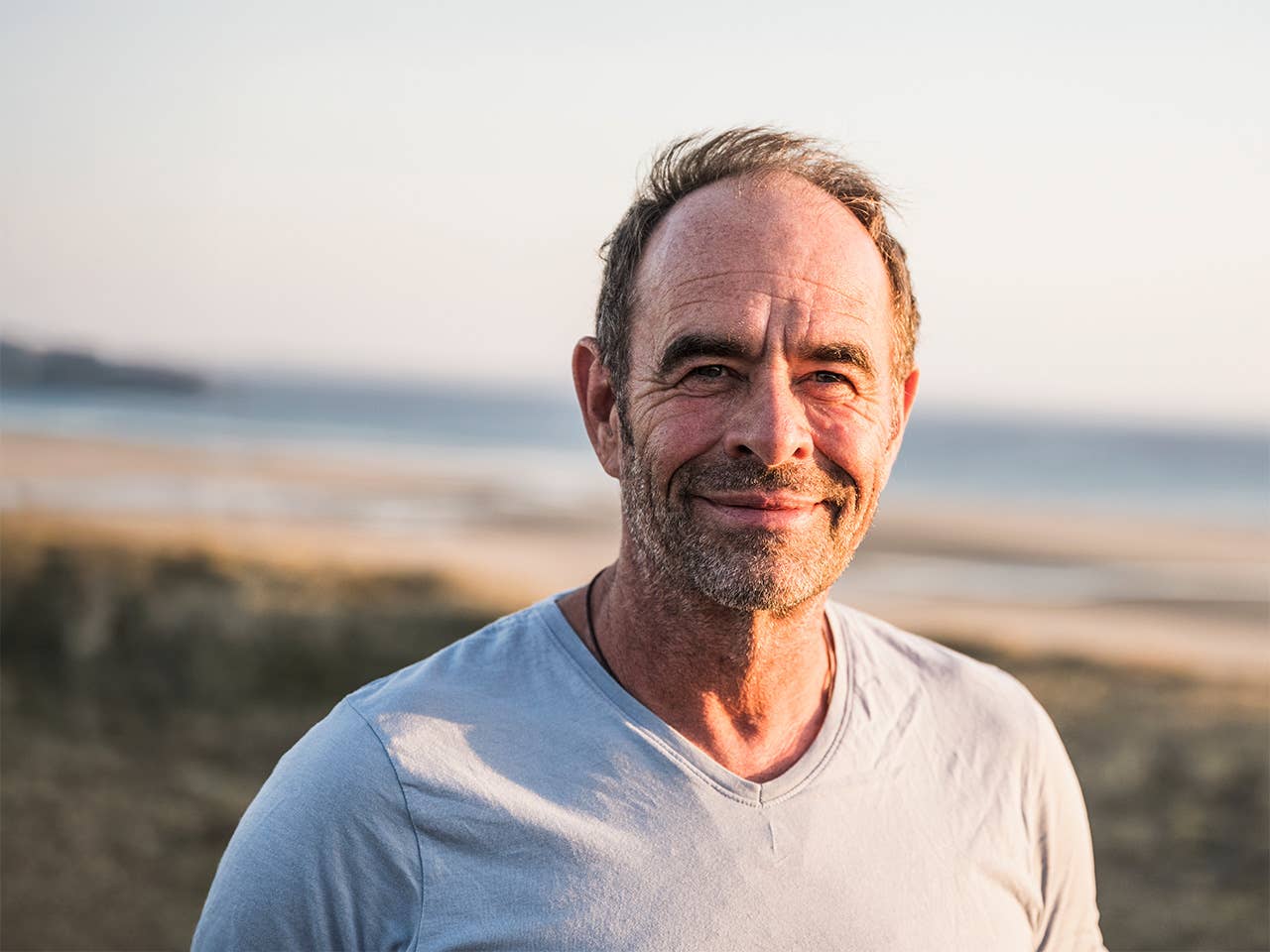 Middle aged white man stands near a beach in the sunset