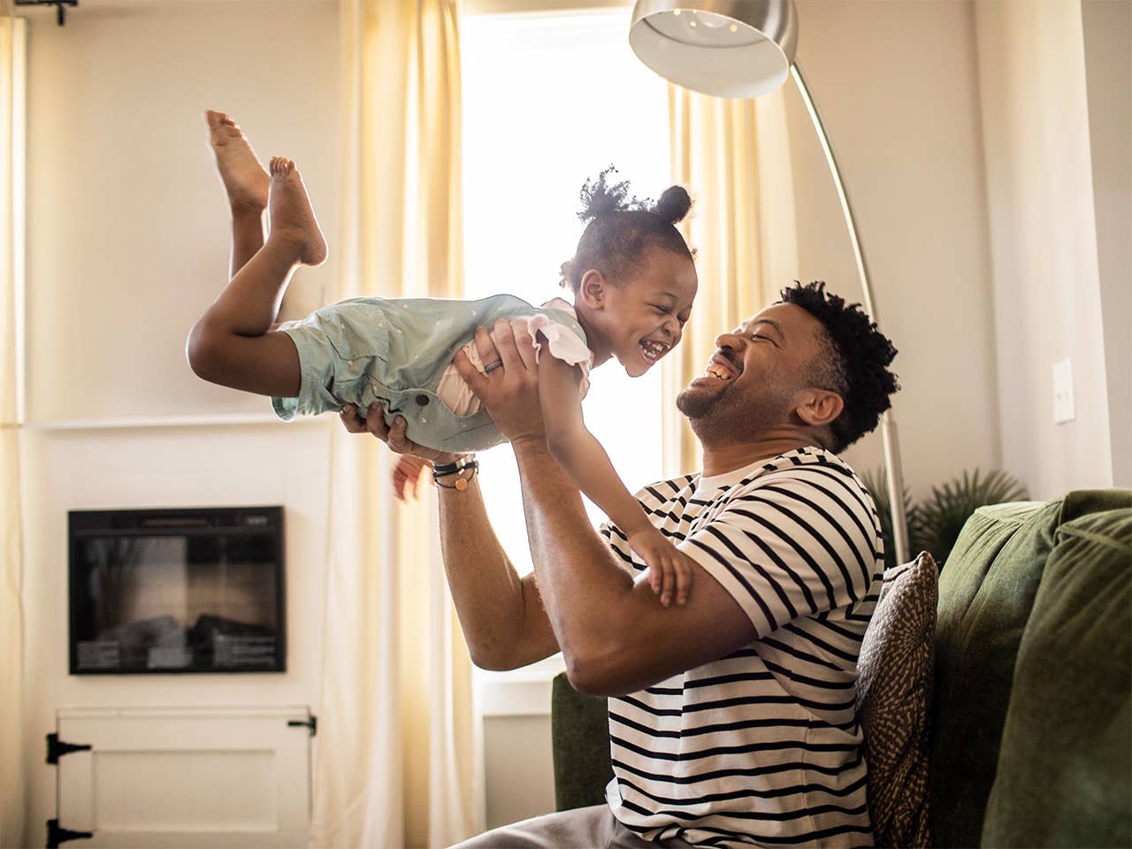 Father and his young daughter playing at home while laughing and smiling.