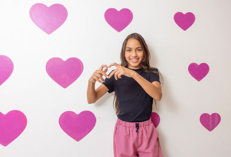 young girl making heart symbol with hands
