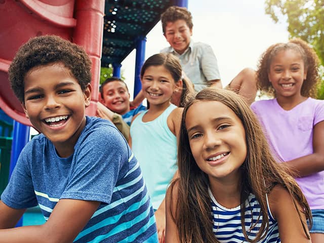 Children playing together on a playground, climbing and sitting near slides during outdoor recreation and social activity.