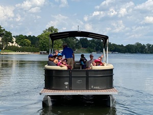  A group of individuals enjoying a leisurely ride on a pontoon boat during a wellness retreat on Lake Huron.