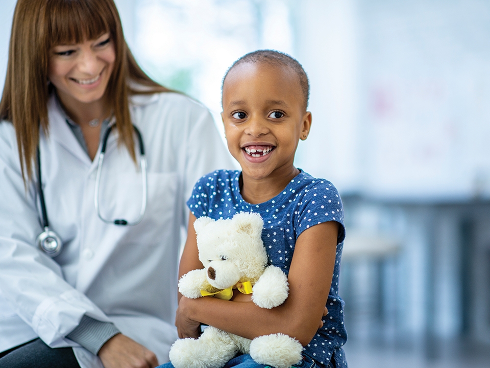 Young patient holds stuffed teddy bear purchased from Corewell Health gift shops.