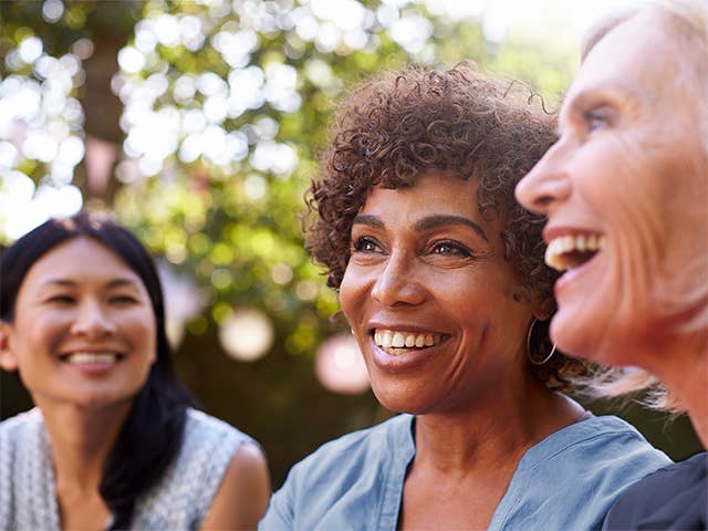 Three women joyfully laughing together at Women’s Wellness Day event.