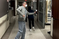 A man wearing a mask is positioned in a hospital hallway, representing the dedication of resident teaching in medicine.