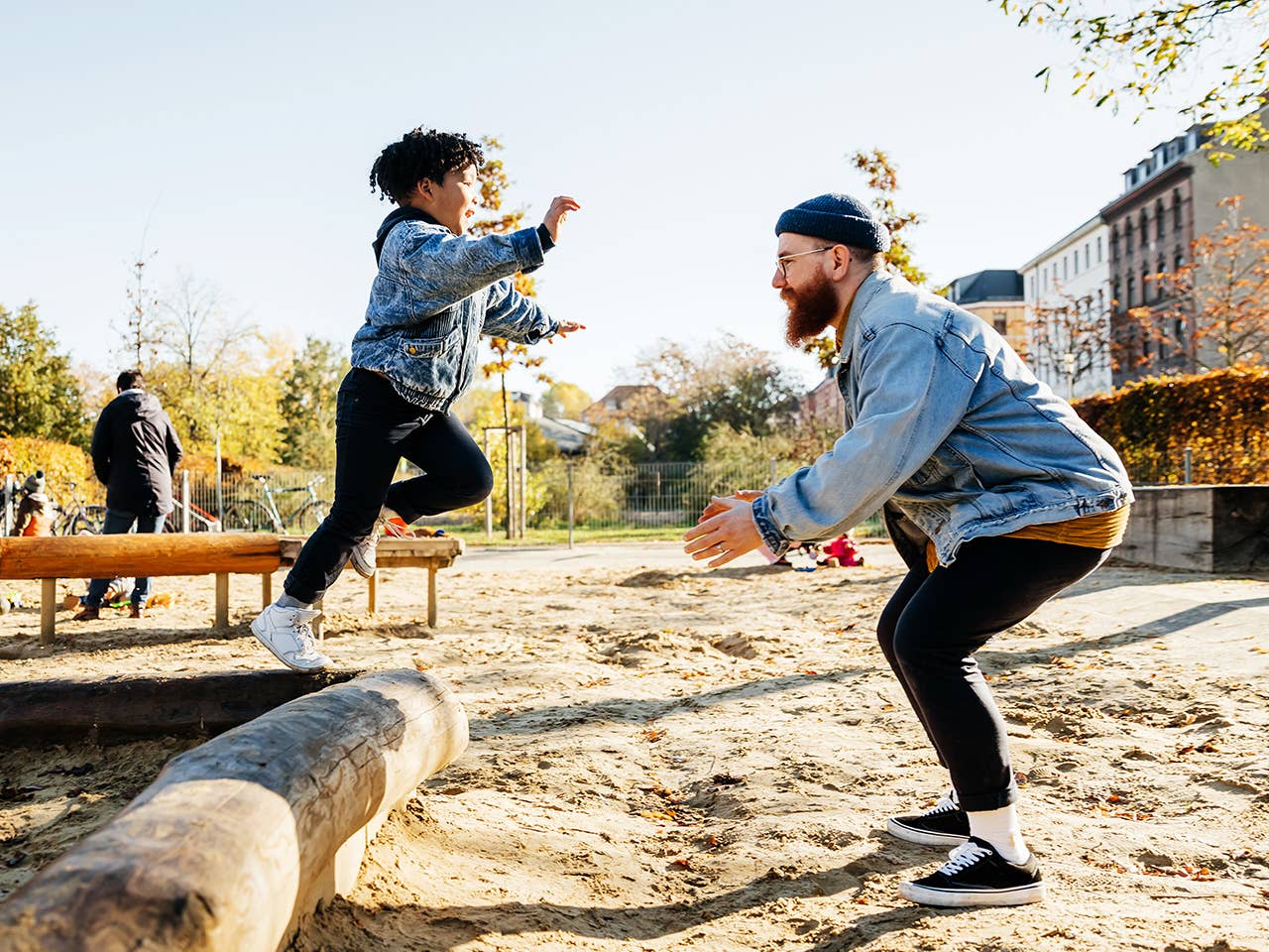 Little boy jumping of a tree log and into his fathers arms.