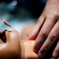A person demonstrates the use of an oxygen tube on a dummy, showcasing essential life-saving techniques.