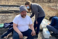 A man and woman sit on the ground with a dog, symbolizing community engagement and diversity in CPR training initiatives.
