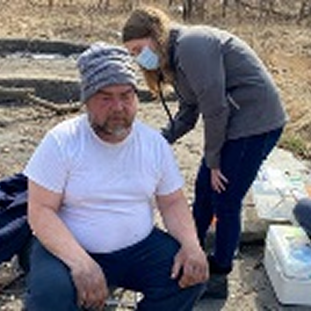 A man and woman sit on the ground with a dog, symbolizing community engagement and diversity in CPR training initiatives.