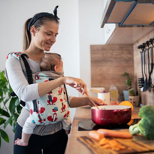 Young mother with her baby while making a meal in the kitchen