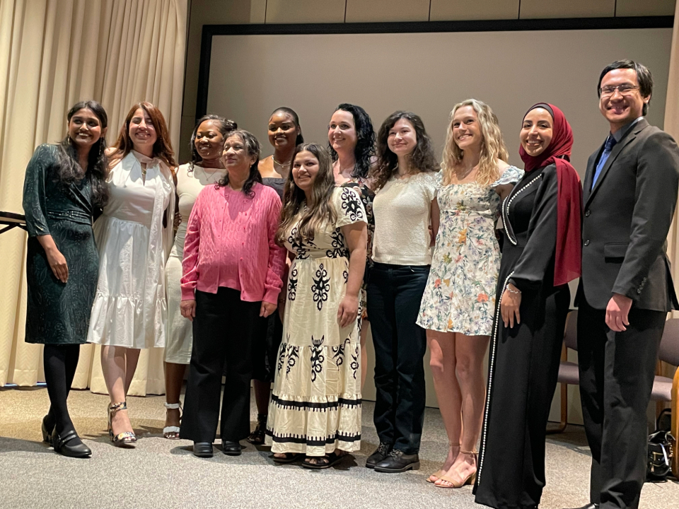 Group of graduating students with an educator posing for a group photo after graduation