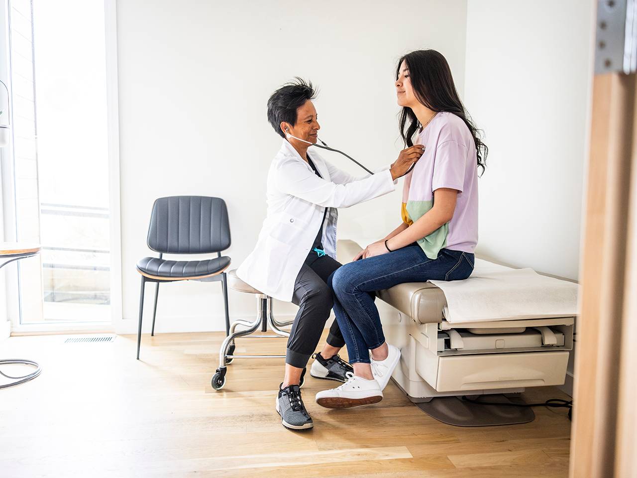 A woman receives a medical examination from a doctor in a clinical setting.