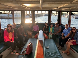 People gathered on the back of a boat, engaging in conversation during a journal club outing.
