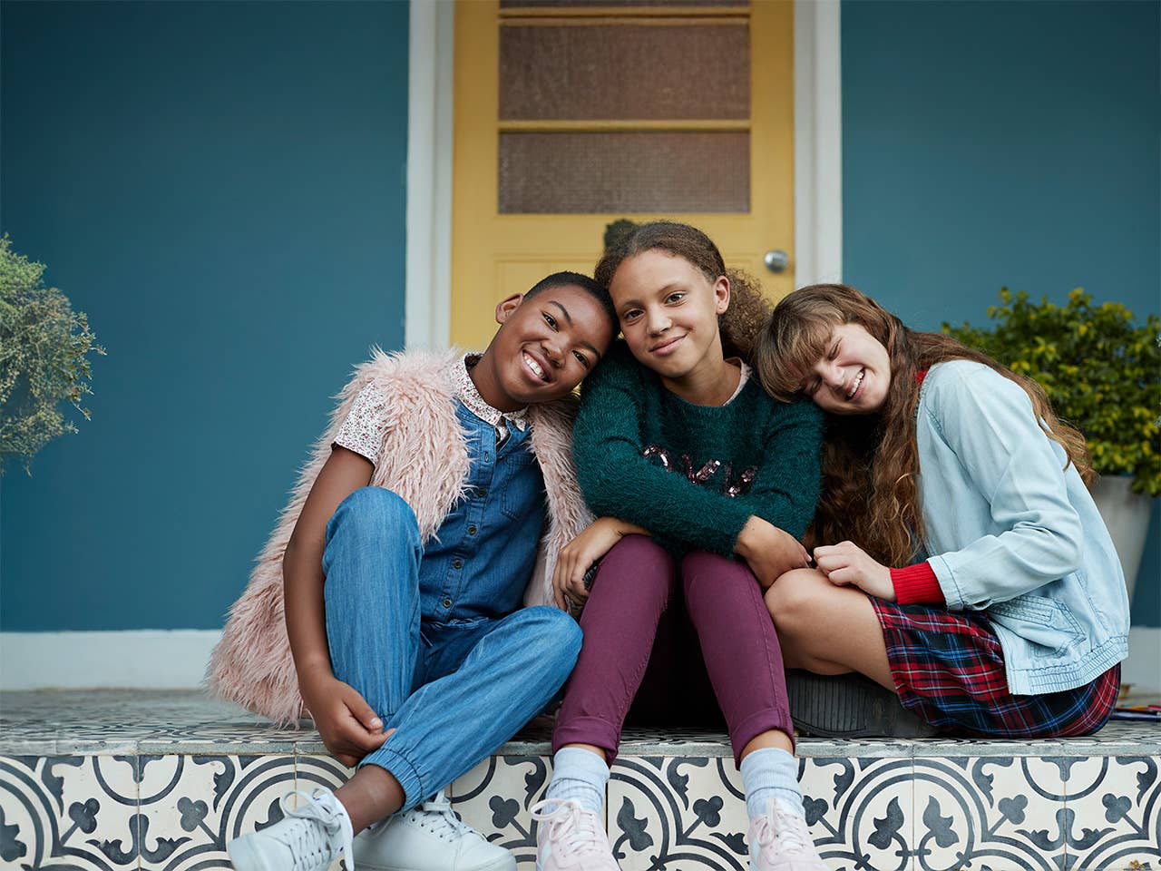 Three young teen girls sitting outside hanging out together.