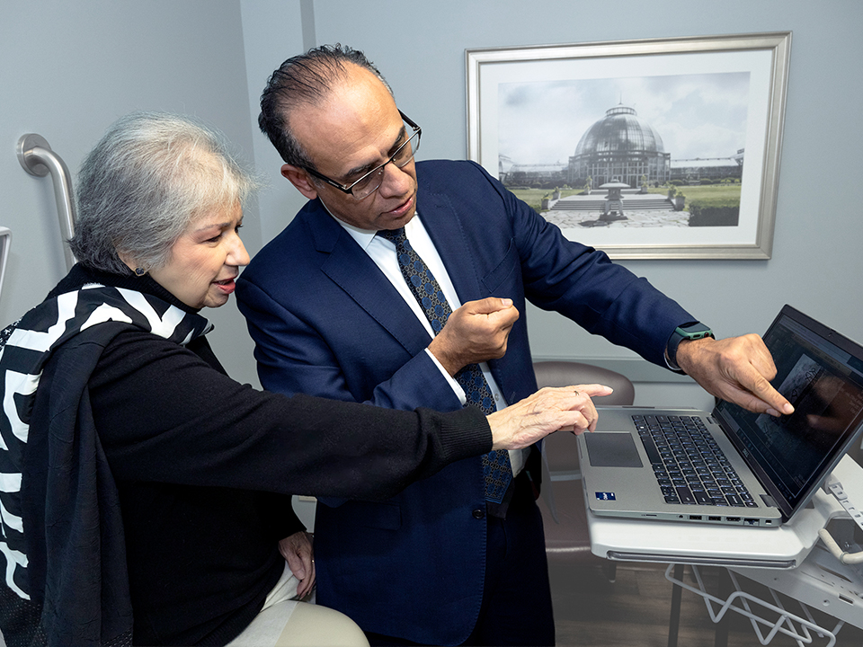 A man and woman are focused on a laptop computer, discussing its content together.