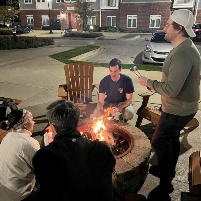 Group of residents talking and having a good time while sitting around a firepit