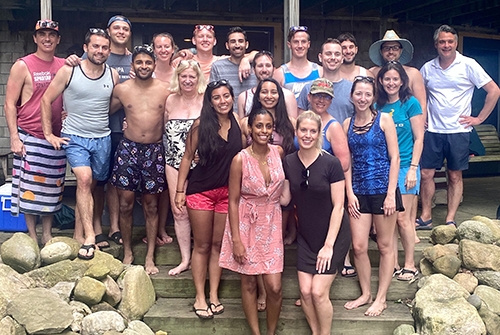 A group of residents happily posing for a photo together on a porch during a community outing.