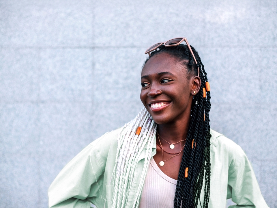 Smiling young Black woman stands outdoors in front of a granite wall