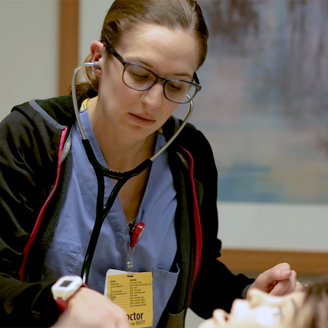 Healthcare learner using a stethoscope during hands-on training at the Corewell Health Lakeland Simulation Training Center.