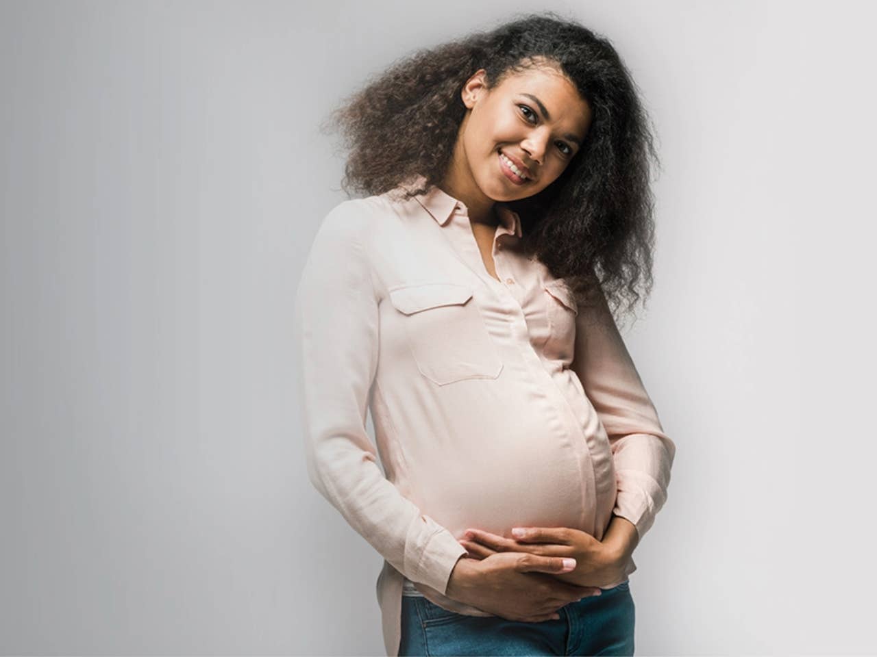 Woman with dark hair holding her belly.