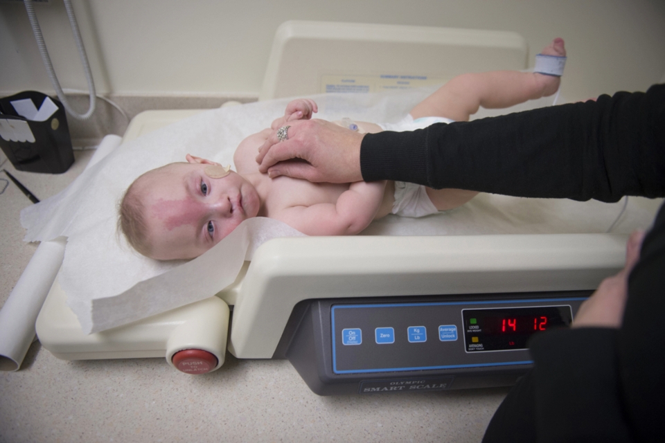 Baby in a diaper lays down on a scale