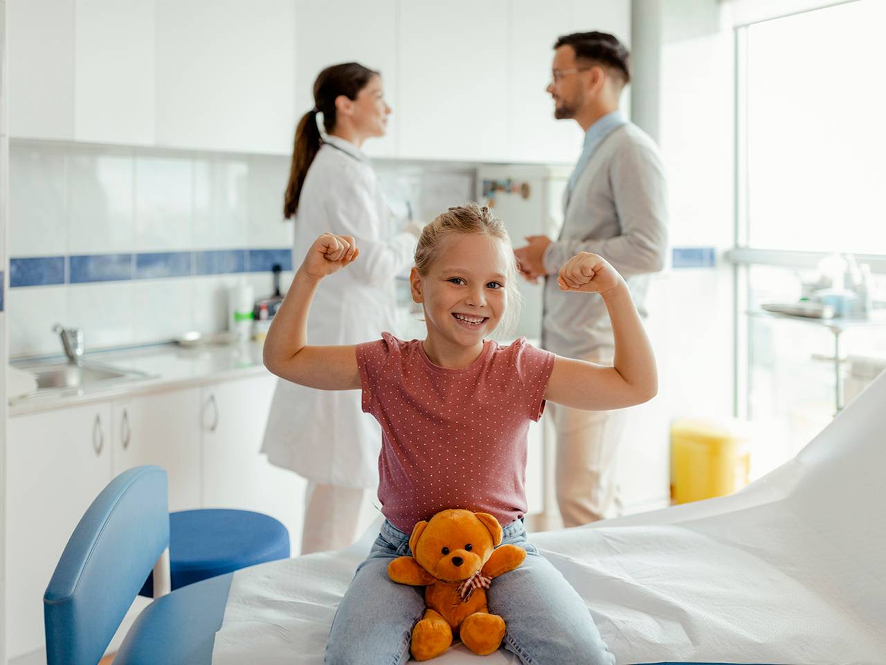 A young girl sitting on a hospital bed, showing her strength in a medical setting.