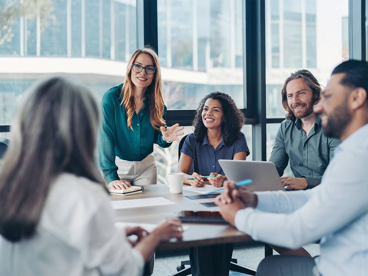 Group of business professionals sitting around a table with computers and phones having a discussion