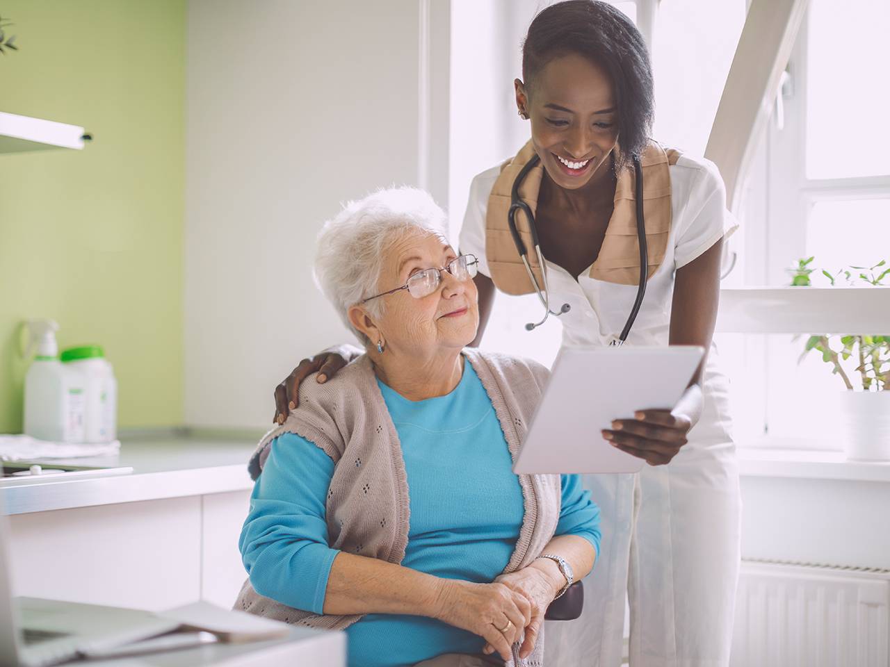 A woman with a stethoscope speaks to an older woman.