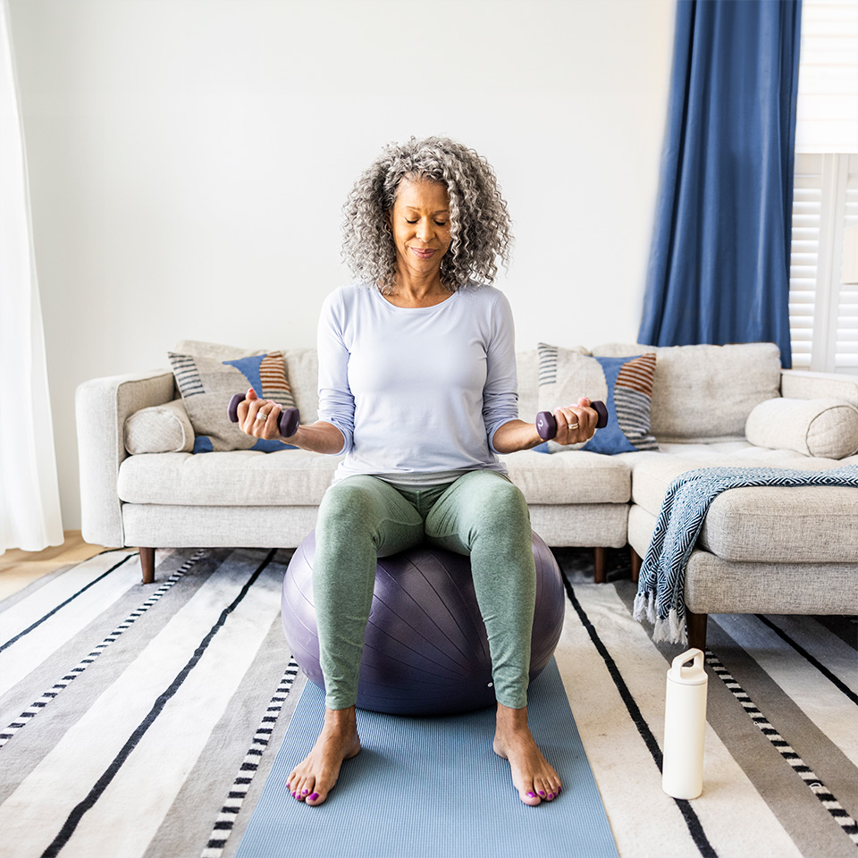 Woman with curly grey hair sitting on an exercise ball