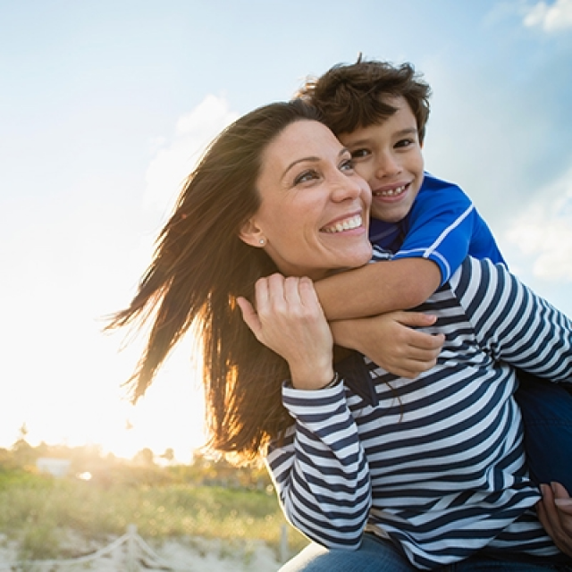 Smiling boy and his mother play outdoors