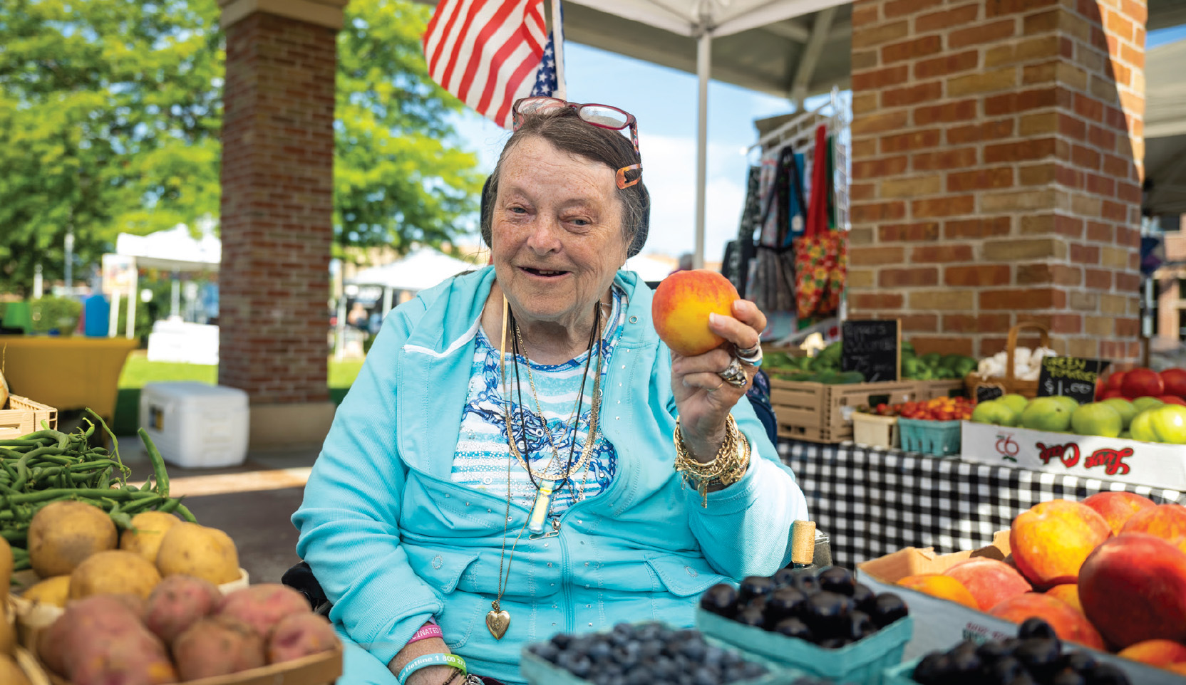 Older woman holding a peach and smiling