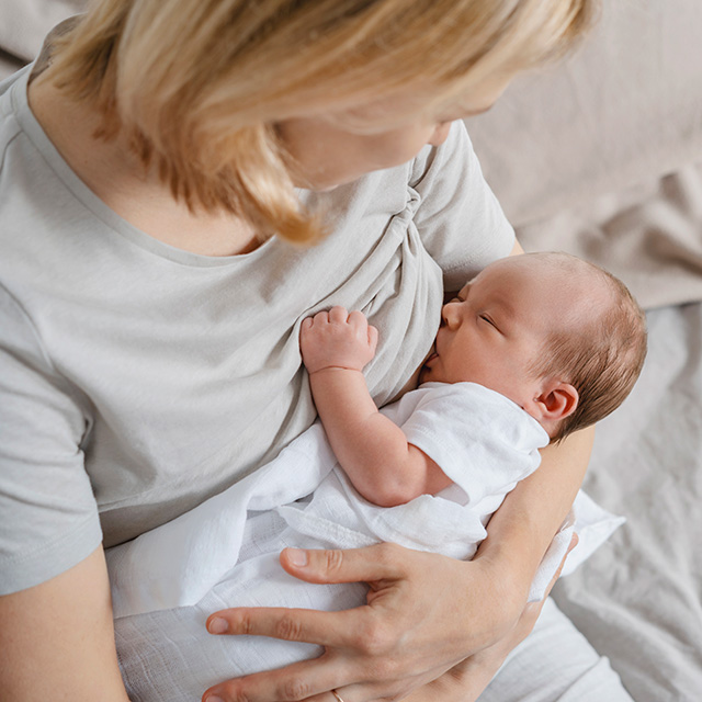 New mother holds her baby to her chest while it breastfeeds