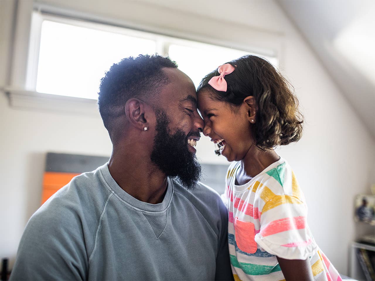 Father and young daughter smiling at each other.