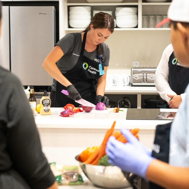 Staff member chopping vegetables during a cooking class she is teaching
