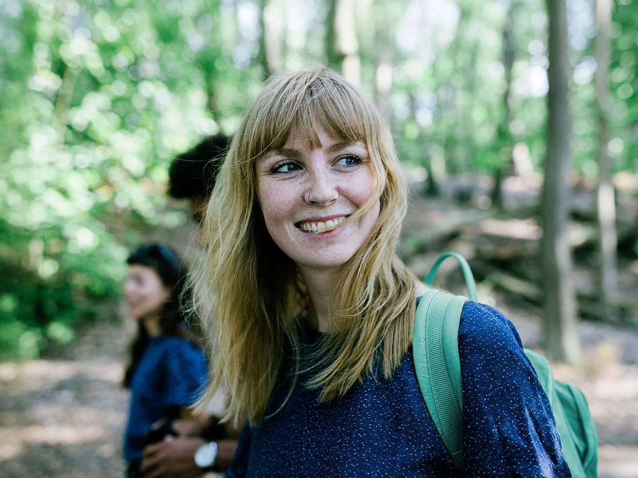 Young white woman in a navy blue shirt hikes through a forest