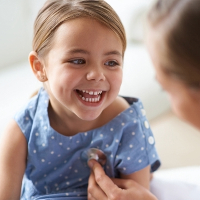 Smiling young girl with a stethoscope on her chest